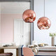 Tom Dixon Copper Pendelleuchten in einem modernen Essbereich mit warmem Metallglanz.