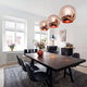 Moderne Esszimmer mit Tom Dixon Copper Pendelleuchten und stilvollem Holztisch.