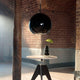 Moderne schwarze Pendelleuchte in Rundform über einem Tisch, stilvolle Inneneinrichtung, minimalistisches Design.