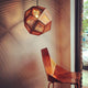 Tom Dixon Etch Metall Hängeleuchte Effektlicht über einem modernen Holzstuhl in einem stilvollen Raum.