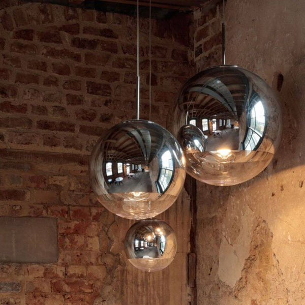 Tom Dixon Mirror Ball 3er Mobile Galerieleuchte in einer stilvollen Umgebung mit reflektierendem Licht.