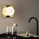 Tom Dixon Plane Wandleuchte Goldfarben in modernem Wohnzimmer mit Glaskugel und goldfarbenem Rahmen.