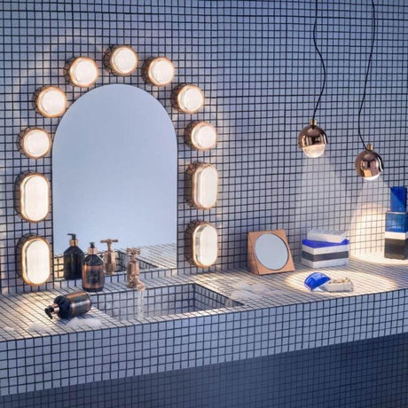 Tom Dixon Spot-vegglampe med glasslinse på moderne bad med mosaikkvegg og servant.