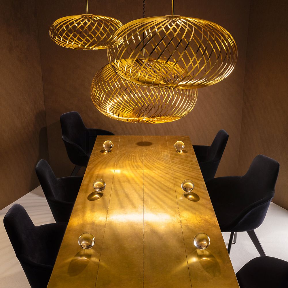 Tom Dixon Spring LED Hängelampe in gold über einem modernen Esstisch mit stilvollen Stühlen.