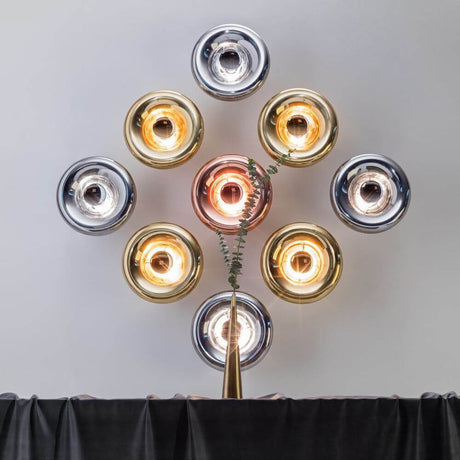 Tom Dixon Void Wandleuchte verspiegelt Ø 30cm in einer kreativen Anordnung mit verschiedenfarbigen Lampenschirmen.