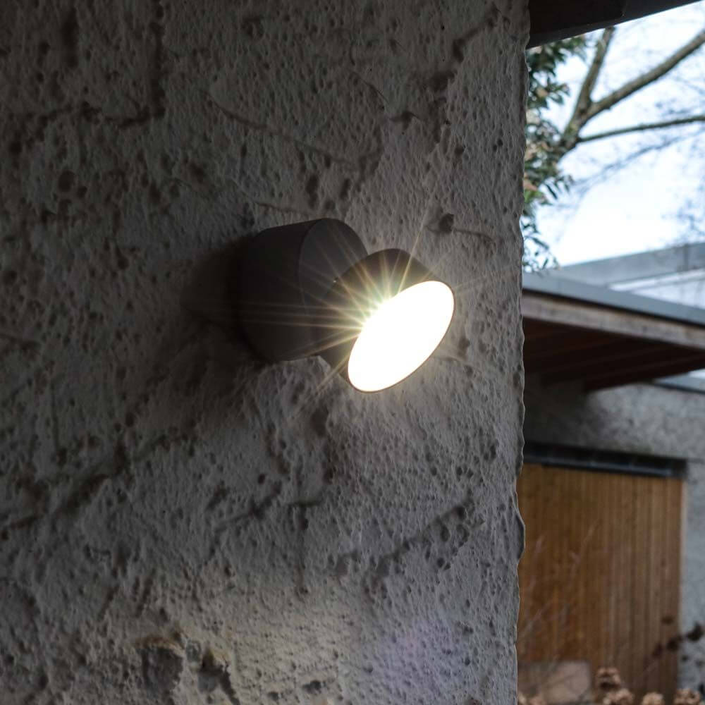 Trumpet L 90° schwenkbare LED-Außenwandleuchte IP54 Anthrazit an Wand mit Lichtstrahl.