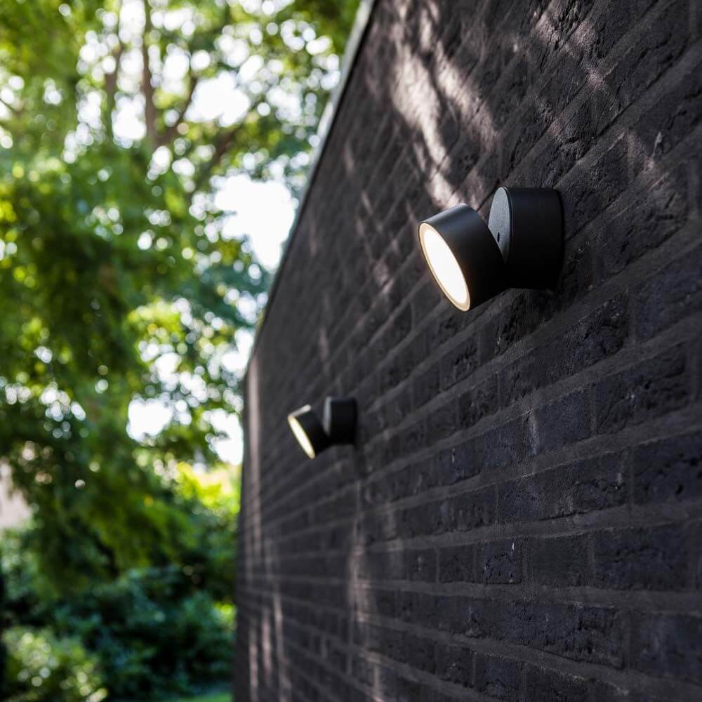 Trumpet L 90° schwenkbare LED-Außenwandleuchte IP54 Anthrazit an einer Wand im Garten.