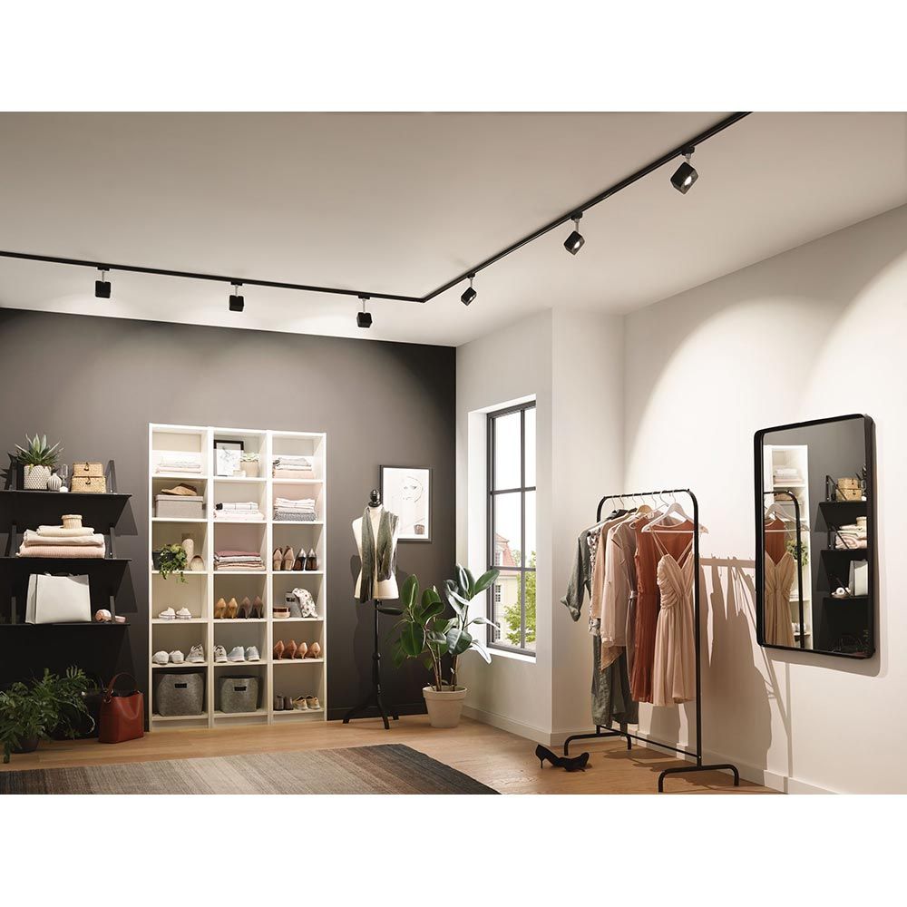 Moderne Ankleide mit schwarzem U-Rail Beleuchtungssystem, Kleiderschrank und eleganter Kleidung.