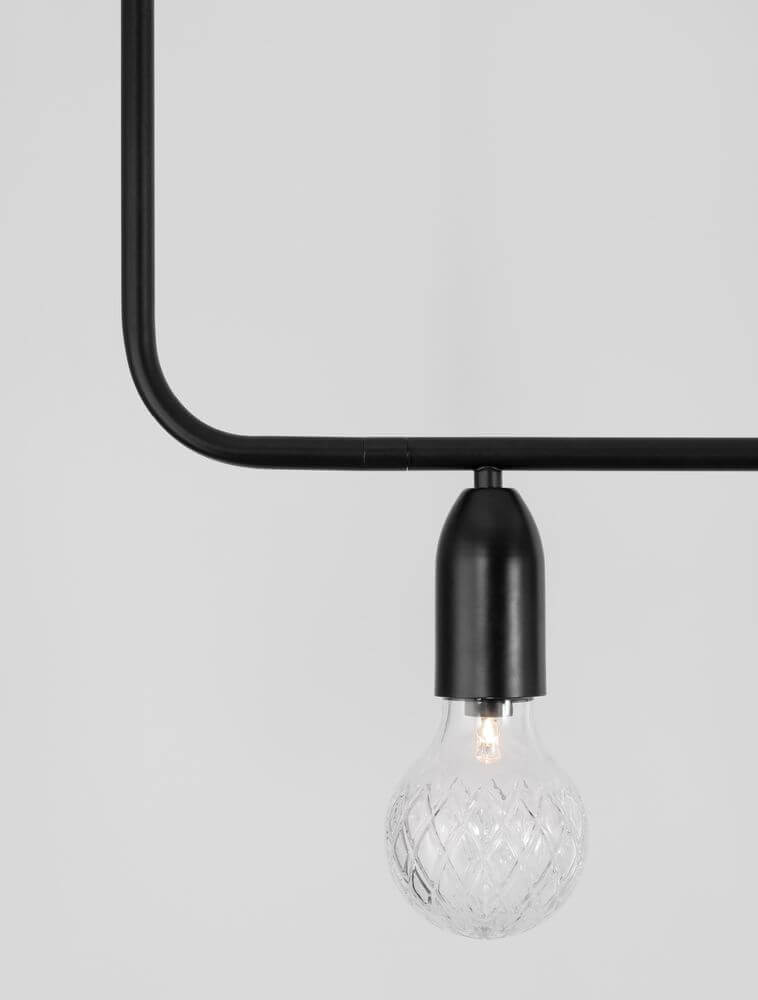 Detail der Veda Pendelleuchte mit schwarzem Rahmen und transparenter Glaskugel, modern und elegant.