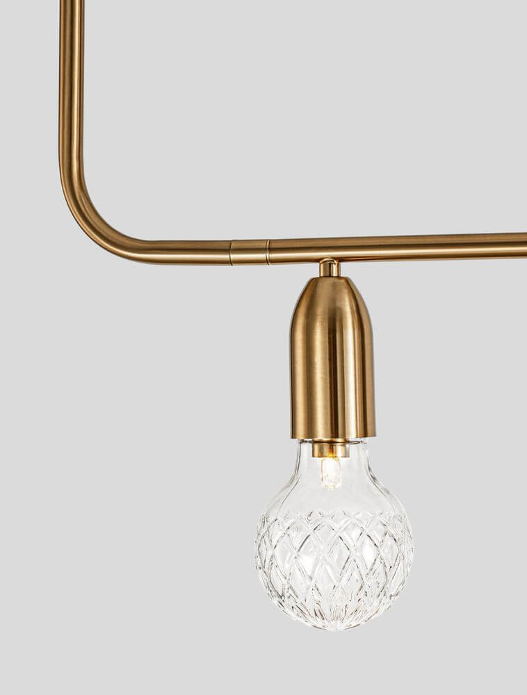 Detailansicht der Veda Pendelleuchte mit goldfarbener Fassung und klarer Glaskugel, modern und elegant.