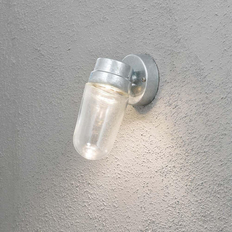Vega LED Applique da esterno 3000K in acciaio zincato, vetro chiaro montato su una parete di cemento.