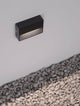 Vision LED Außenwandleuchte 3000K Anthrazit IP54 an einer Wand installiert mit Kiesuntergrund.