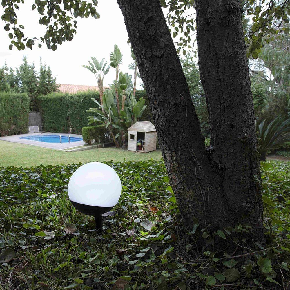 Voila LED Outdoor Hänge- Tisch- & Bodenleuchte USB IP44 im Garten neben einem Baum.