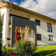 Modernes Einfamilienhaus mit schönem Garten und rotem Sonnenschirm, ideale Planung für Vor-Ort Termin.