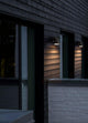 Wand-Außenleuchte Front Single IP44 Schwarz an einer modernen Fassade mit Holzverkleidung.
