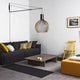 Wandhalterung Varsi 1000 für Pendelleuchten in modernem Wohnzimmer mit schwarzem Sofa und dekorativer Pendelleuchte.