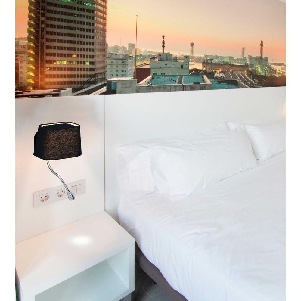 Wandlampe SWEET mit LED-Lesearm Schwarz neben einem Bett in einem modernen Schlafzimmer.