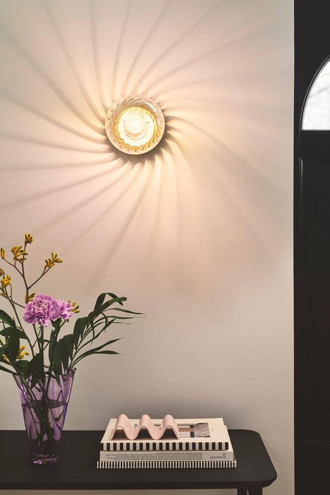 Wandleuchte Chisell an der Wand mit verwirbeltem Glas und glamourösem Lichtspiel im modernen Raum.