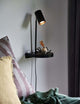 Wandleuchte Cody an einer Wand, minimalistisch mit Ablage und verstellbarem Licht, ideal für Schlafzimmer.