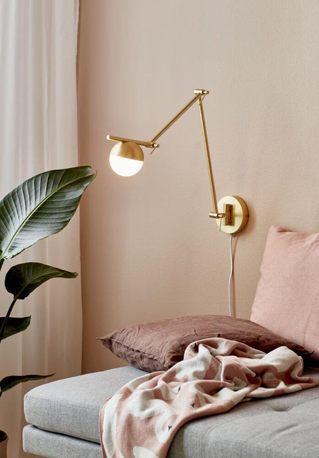 Contina wall light on a wall above a sofa with cushions and a blanket, elegant design with glare-free light.