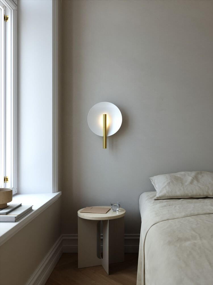 Wandleuchte Furiko an der Wand über einem Bett in einem modernen Schlafzimmer mit neutrals Farbschema.