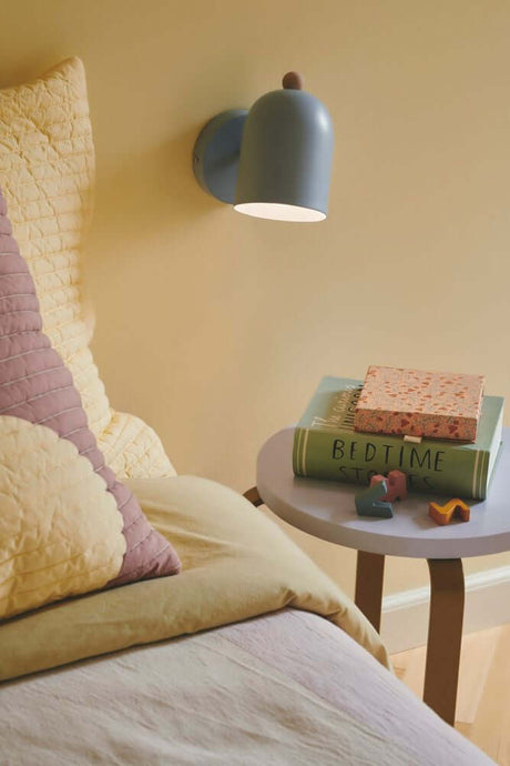 Applique Gaston au mur au-dessus d'une table de chevet avec des livres pour enfants et des jouets.