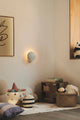 Wandleuchte Konchi in Form einer Muschel an der Wand, sanftes Licht im gemütlichen Raum.
