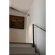 Wandleuchte LINK Bronze an einer Treppe mit Kunstwerk im Hintergrund.