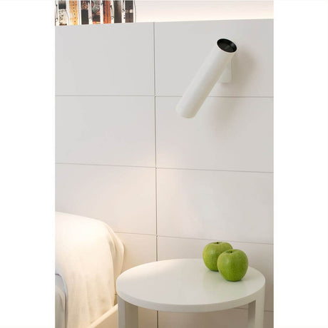 Wandleuchte LINK Weiß an einer weißen Wand, mit Äpfeln auf einem Tisch im Vordergrund.