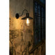 Wandleuchte MARINA Schwarz an einer Wand mit vintage Charakter, strahlt warmes Licht aus.