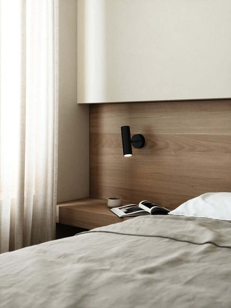 Wandleuchte MIB 6 an einer Wand über einem Nachttisch im skandinavischen Stil, ideal für moderne Schlafzimmer.