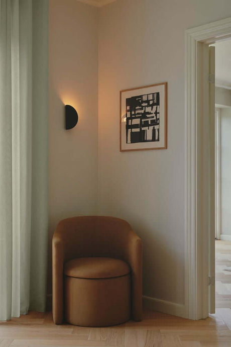 Applique murale Model 2110 au mur au-dessus d’un fauteuil beige dans une pièce moderne.