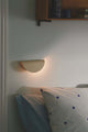 Wandleuchte Model 2110 an einer Wand, strahlt warmes Licht aus und ergänzt das Schlafzimmerambiente.