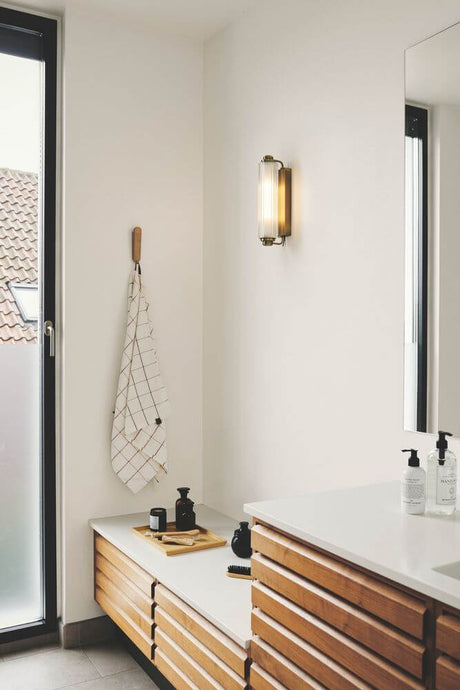 Applique murale Nimal Double IP44 sur un mur de salle de bain moderne avec des armoires en bois.