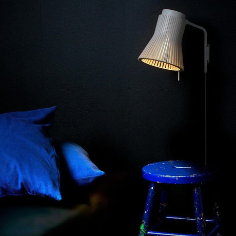 Petite 4630 wall light made of wood Ø 20 cm next to a blue stool and cushion in Scandinavian design.