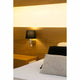 Wandleuchte ROOM mit LED-Leselicht 2700K Nickel, Schwarz an Wand neben Bett mit Kissen.