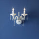 Wandleuchte Rosano 2-flammig Weiß an blauer Wand mit elegantem Design und Kristallakzenten.