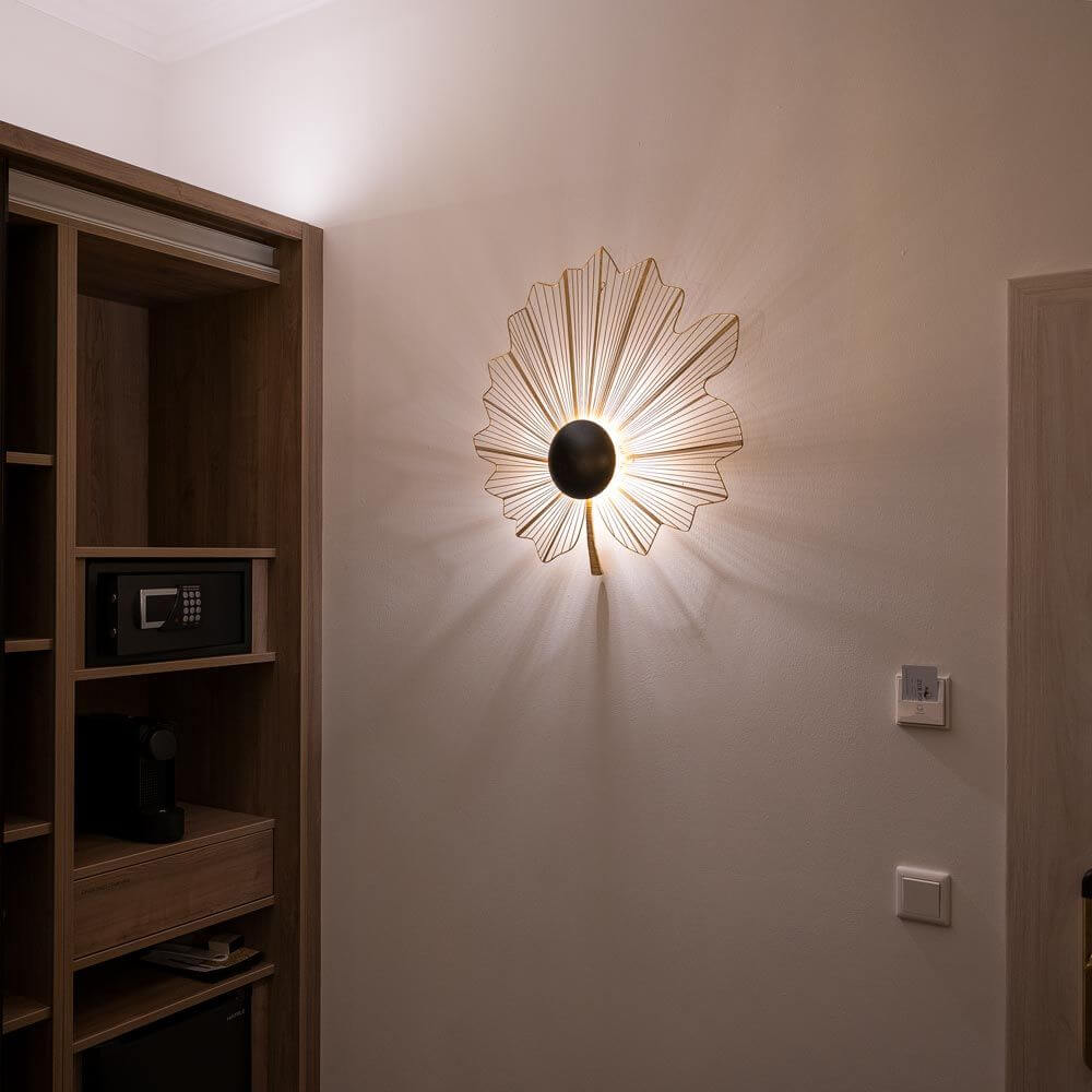 Wandleuchte Tremolo Klein Eisendraht Gold-Braun-Schwarz an einer Wand mit warmem Licht.