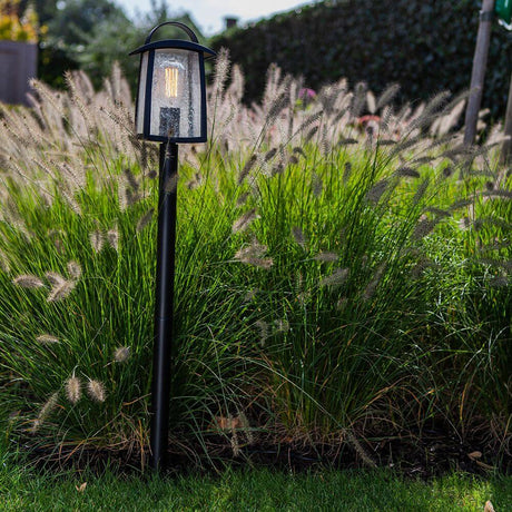 Wegeleuchte Kelsey IP44 103cm Schwarz in einem Garten zwischen Gräsern.
