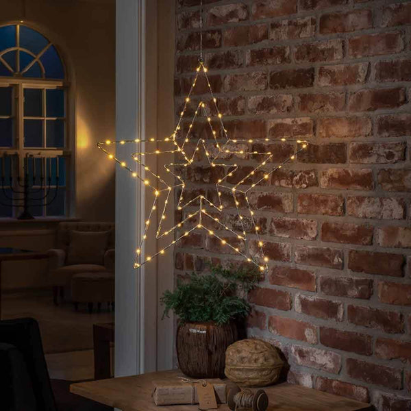 Weihnachtlicher LED Stern mit 112 Lichtpunkten IP20 an einer Ziegelmauer hängend, mit warmem Licht.