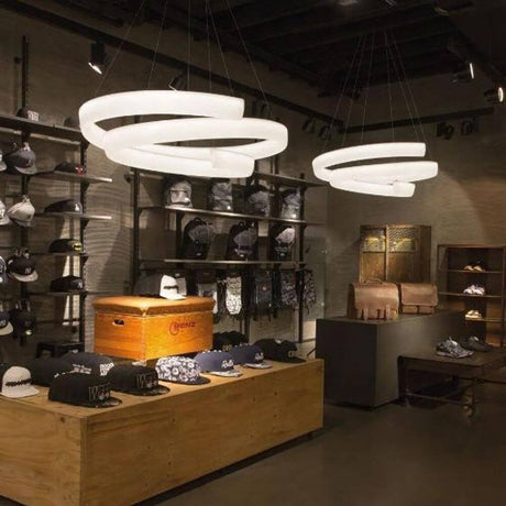 LED-hengelampe Cyclone 7000 lm Hvit i moderne butikkinteriør med stilige hatter og tilbehør.