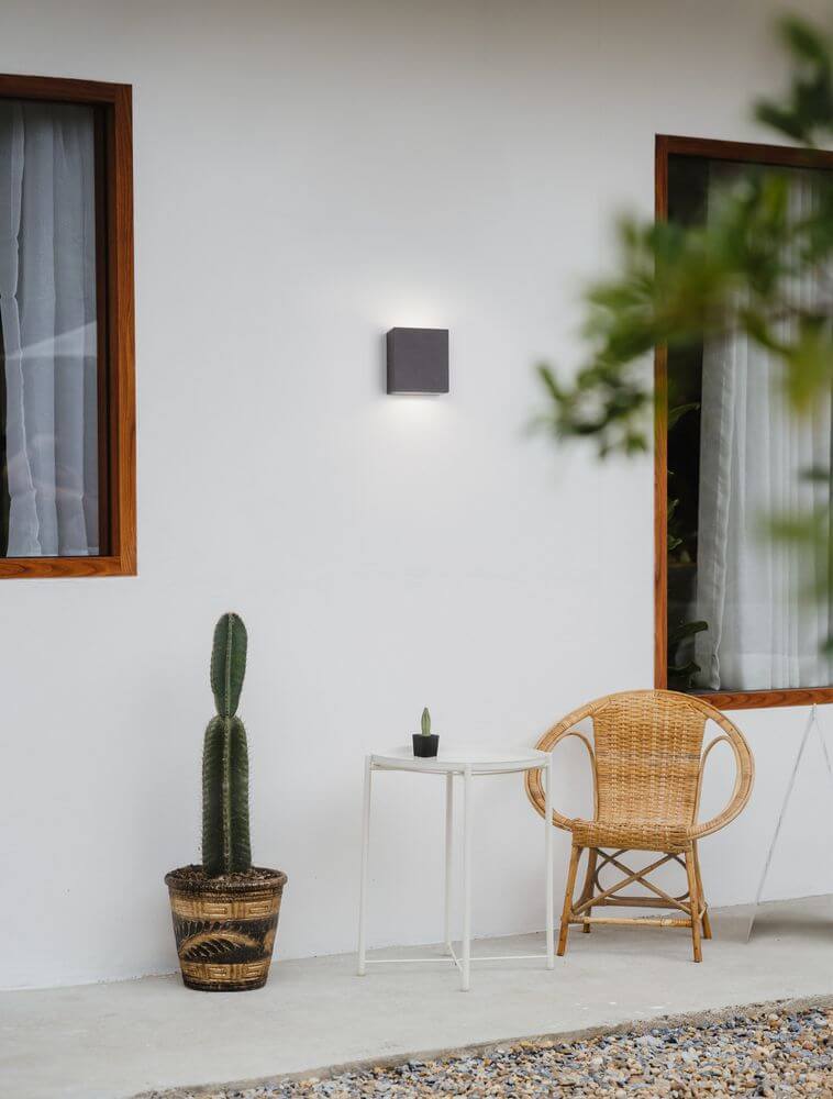 Zaro LED Außenwandleuchte 3000K Anthrazit IP65 an einer Wand, umgeben von Pflanzen und einem Gartenstuhl.