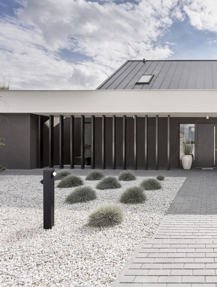 Moderne Außenansicht eines Hauses mit ZELDA LED Außenpollerleuchte, elegant gestaltet und in Schwarz.
