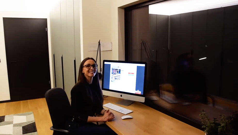 Junge Frau sitzt an einem Schreibtisch, arbeitet an einem iMac in einem modernen Büro.