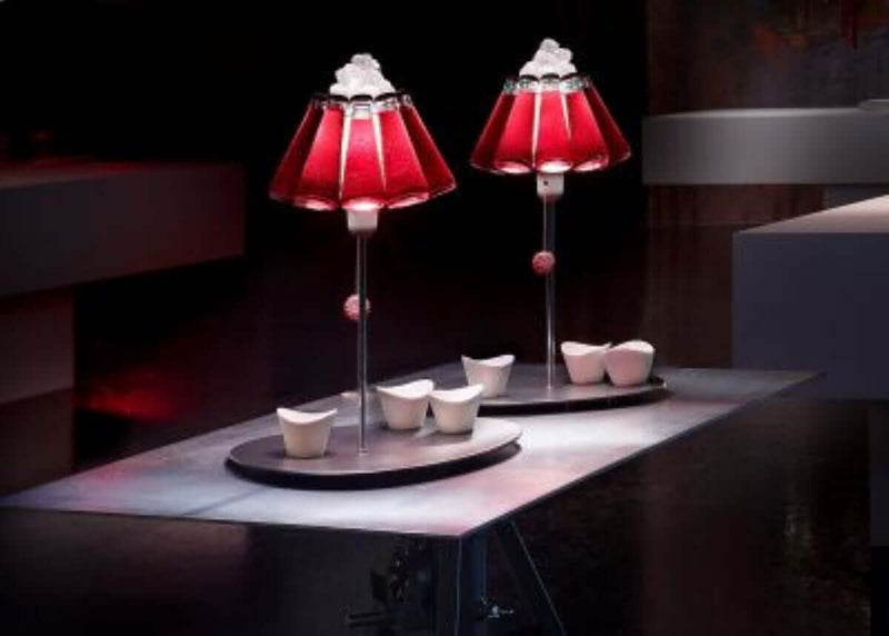Zwei elegante rote Lampen auf einem modernen Tisch mit dekorativen Tassen im Hintergrund.