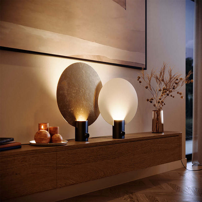 Moderne Tischlampen auf einer Holzkommode, mit warmem Licht und dekorativen Elementen im Hintergrund.