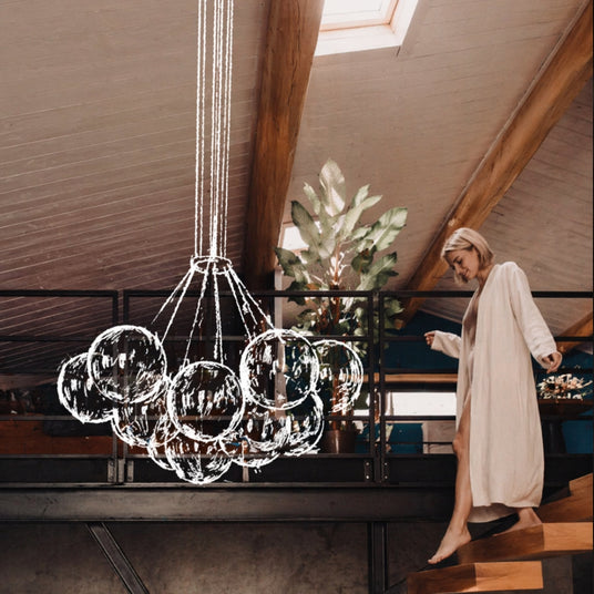 Elegante Glaskronleuchter in modernem Raum mit einer Frau in Morgenrobe auf der Treppe.
