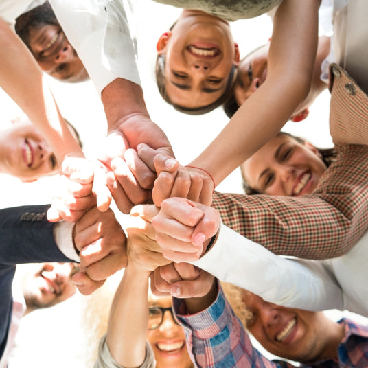 Verschiedene Menschen legen ihre Hände zusammen, um Gemeinschaft und Zusammenarbeit zu zeigen.