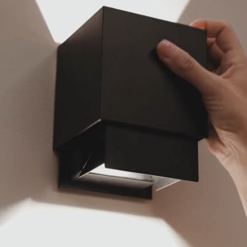 s.luce Ixa LED Wandlampe mit Bewegungsmelder an einer Wand montiert, Benutzer schaltet das Licht ein.