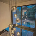 s.luce Orb XL Galerieleuchte 8-flammig, schwebende Glas-Hängeleuchten in stilvollem Design mit nachtblauen Fensterblick.